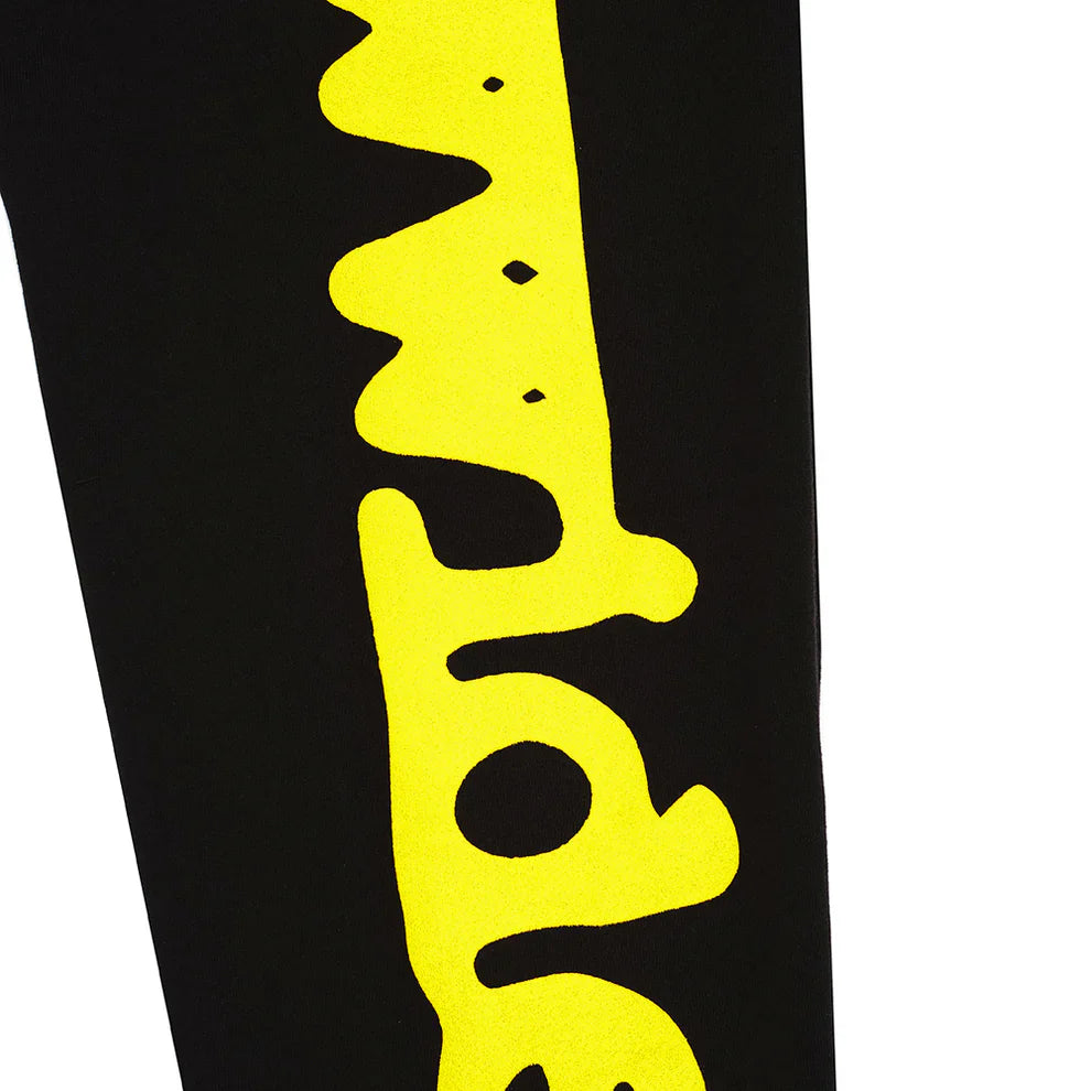 A close-up of Sp5der Sweatpants Black Yellow Side Logo Print shows bold wavy yellow text on 100% cotton, perfect for streetwear jogger pants fans.
