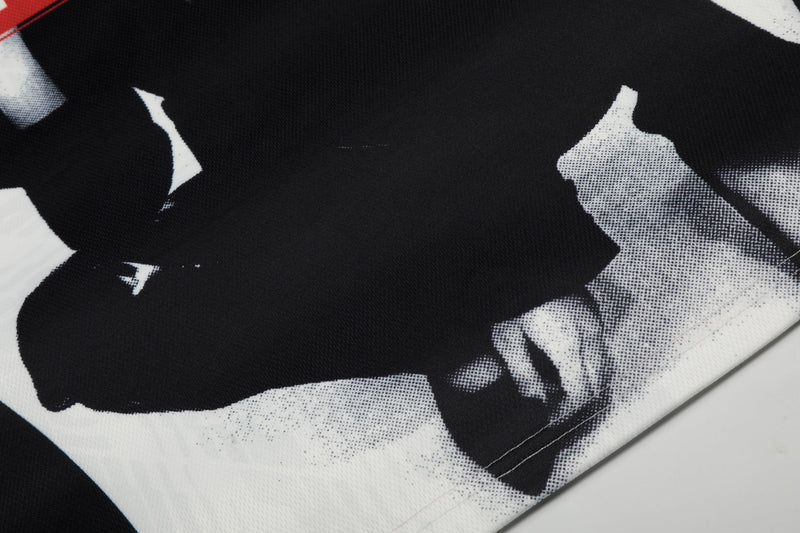Close-up of black and white graphic mesh soccer jersey fabric with bold abstract print and stitched hem