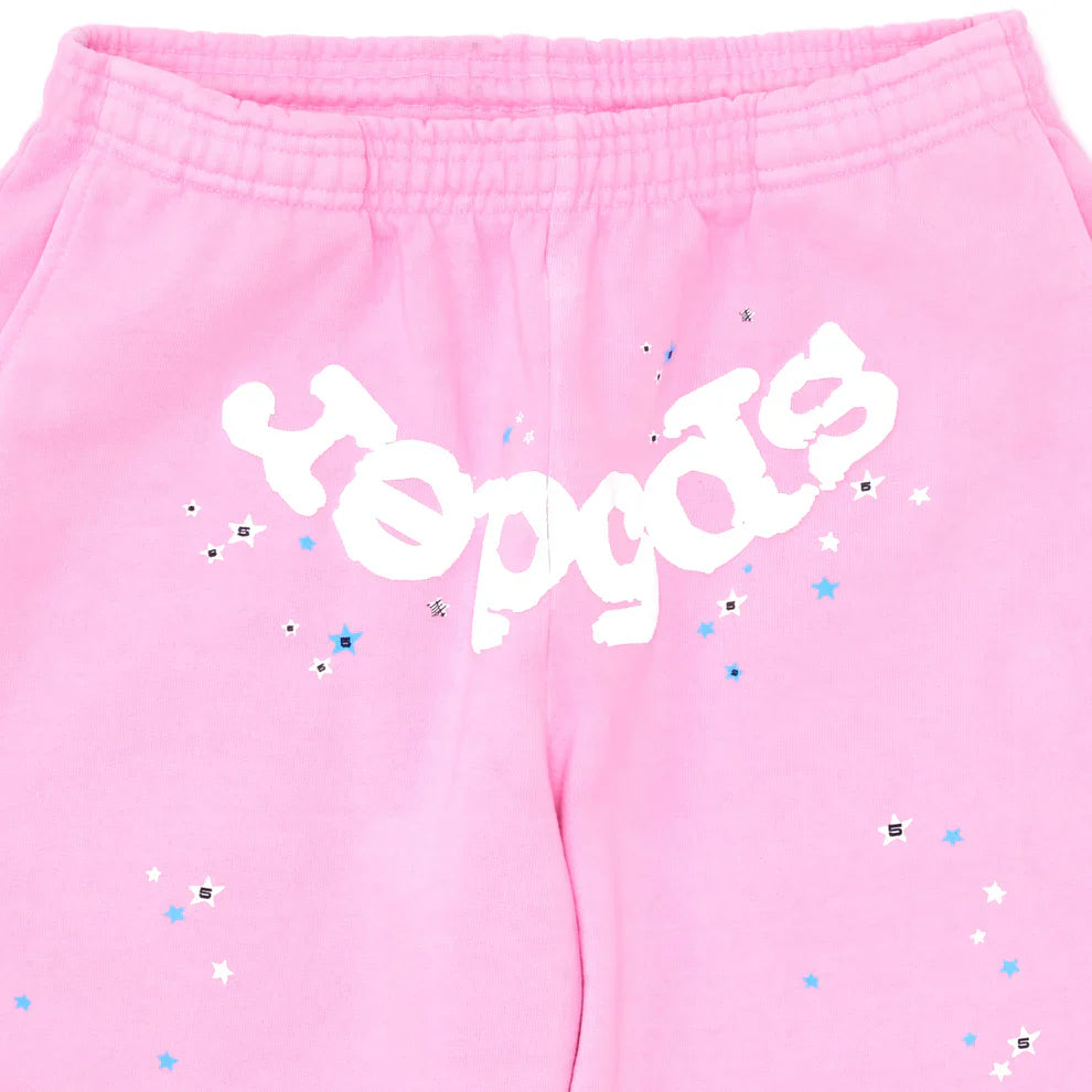Close-up of Sp5der Sweatpants – Unisex Light Pink Cotton Sweatpants with a bold front logo and blue, white, and silver star print accents.