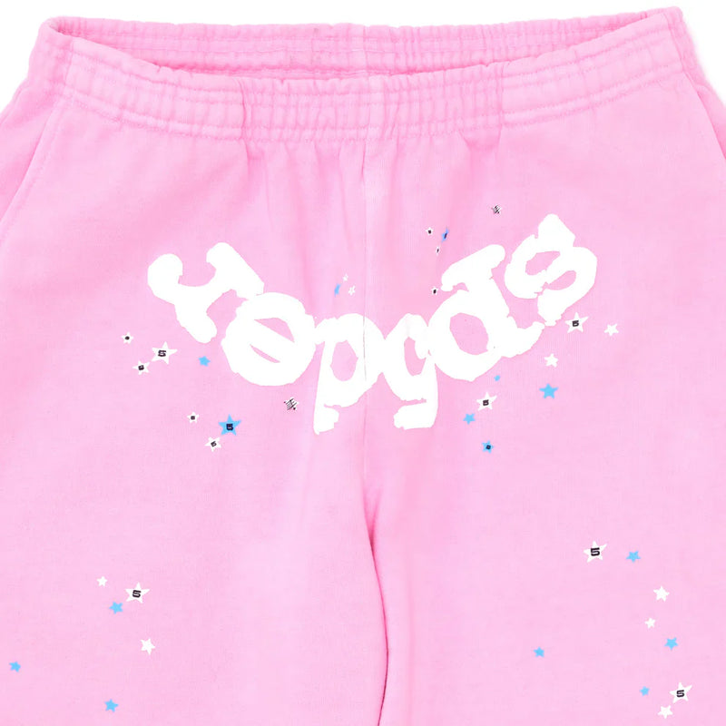 Close-up of Sp5der Sweatpants – Unisex Light Pink Cotton Sweatpants with a bold front logo and blue, white, and silver star print accents.