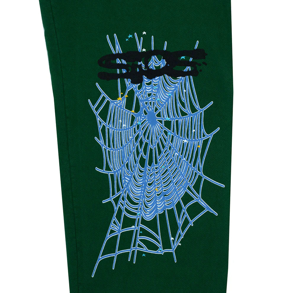 A close-up of 100% cotton Sp5der sweatpants for men in dark green with a large blue spider web graphic, black scribble, and small stars above it; relaxed fit streetwear jogger pants.