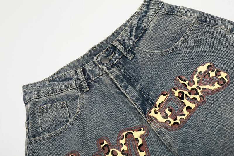 Close-up of front waistband and leopard print patch on blue washed denim jeans