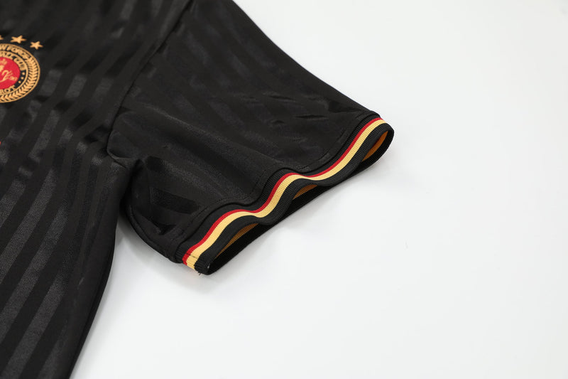 Black mesh soccer jersey tee with striped sleeve cuff and embroidered crest on white background