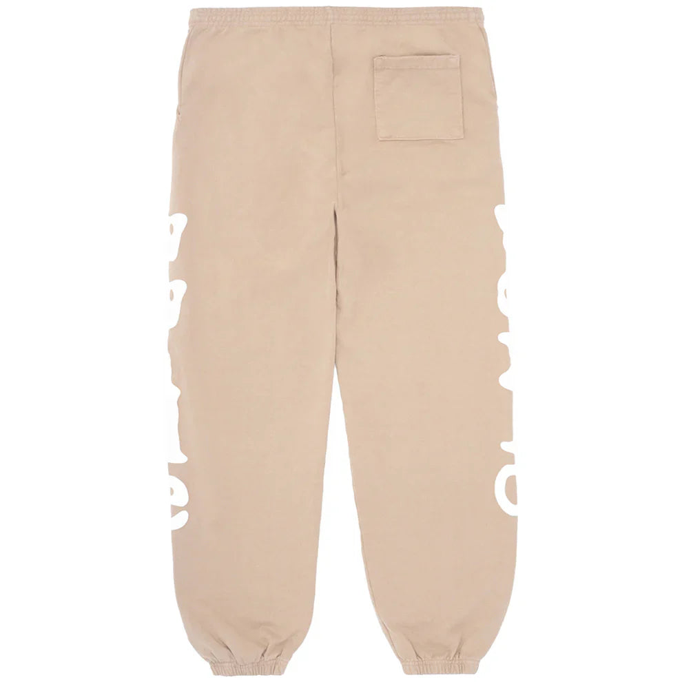 The 100% Cotton Sp5der Sweatpants for Men are beige streetwear jogger pants with a relaxed fit, side logo graphics, an elastic waistband and cuffs, and a right back pocket—offering signature comfort and style.