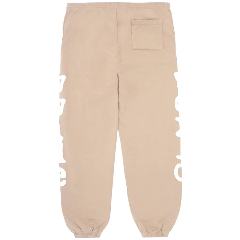 The 100% Cotton Sp5der Sweatpants for Men are beige streetwear jogger pants with a relaxed fit, side logo graphics, an elastic waistband and cuffs, and a right back pocket—offering signature comfort and style.