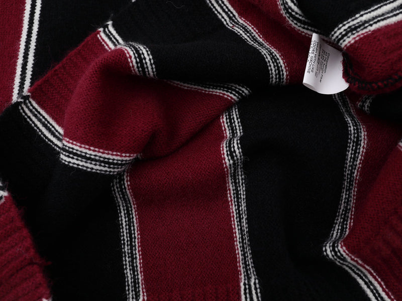 Close-up of sweater care label on burgundy and black striped knit fabric
