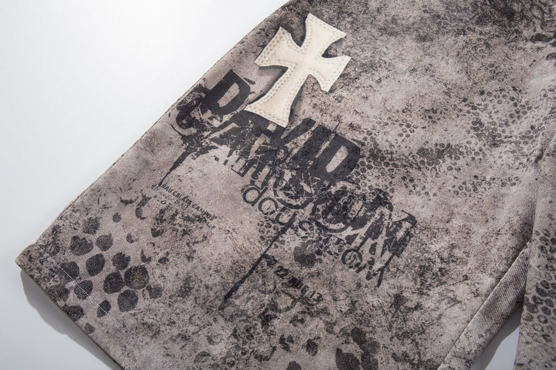 Close-up of black graphic print on washed gray denim shorts with white cross patch