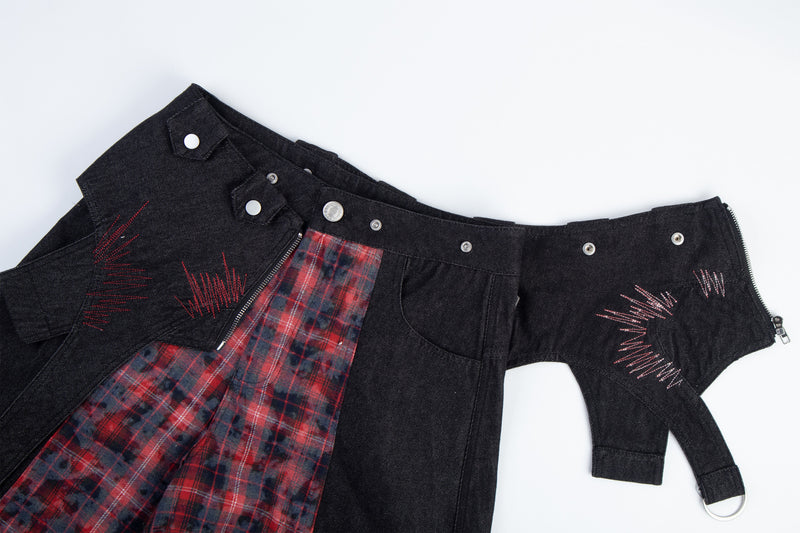 Flat lay of black cargo pants with red stitched details, plaid panel, and ring-tab pockets