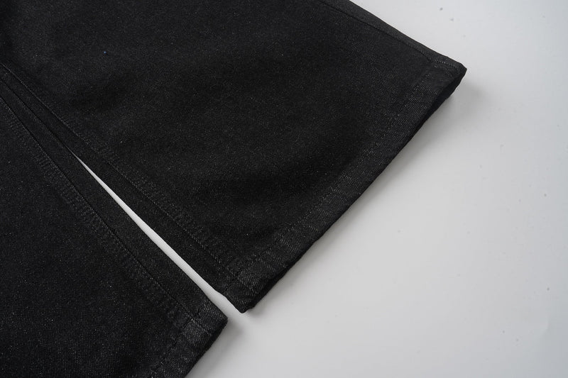 Black wide-leg jeans leg close-up showing straight hem and denim texture
