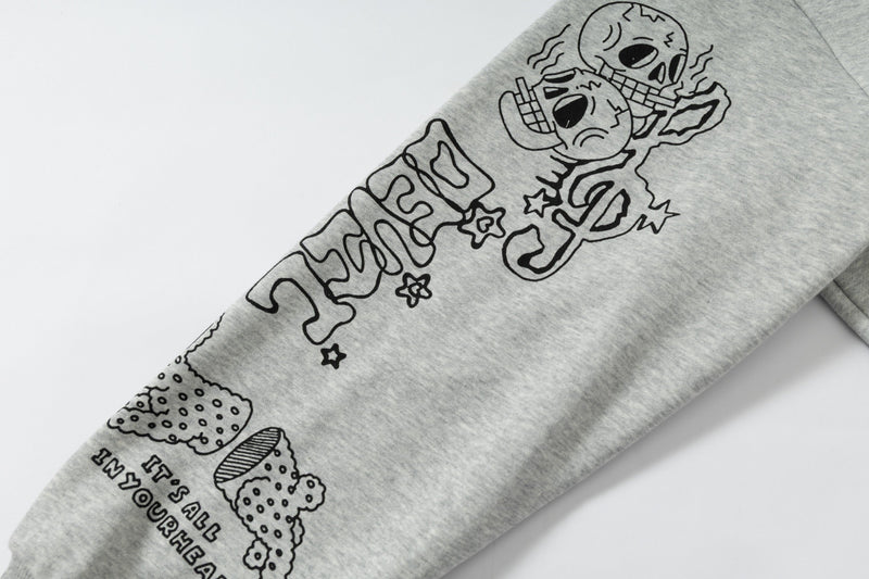 Close-up of sleeve graphic with skulls and doodle lettering on grey hoodie
