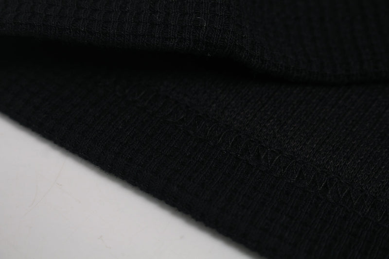 Close-up of black knit fabric with ribbed cuff, showing the texture of a streetwear graphic tee sleeve
