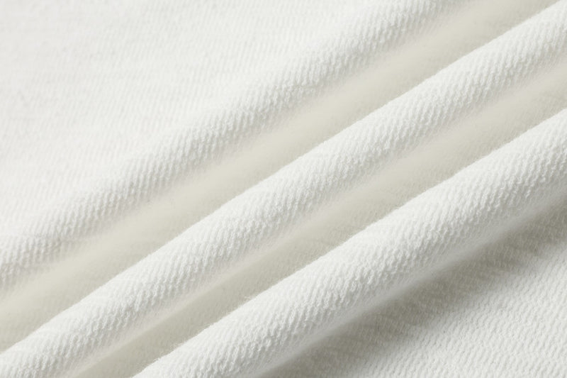 Close-up of white textured polo shirt fabric with soft diagonal folds and a clean streetwear look