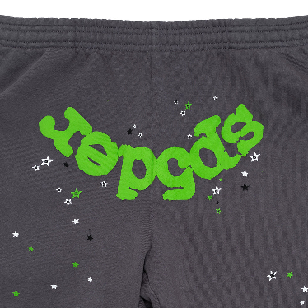 The 100% Cotton Sp5der Sweatpants for Men are dark grey jogger pants featuring a relaxed fit, elastic waistband, and bold green logo graphic surrounded by small white, black, and green stars.