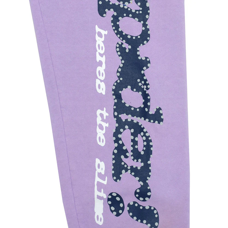 The 100% Cotton Sp5der Sweatpants are unisex lavender jogger pants featuring a vertical logo with star details and a relaxed fit, perfect for streetwear.