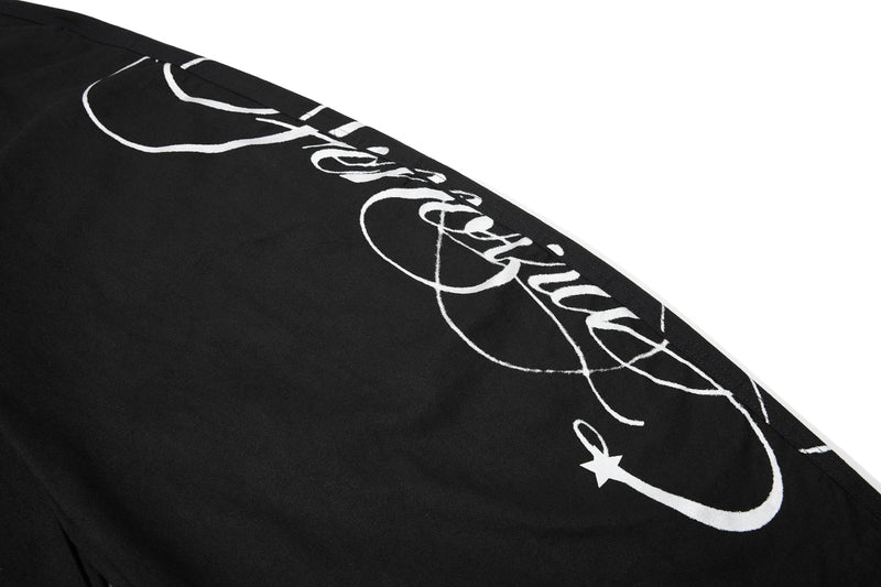 Close-up of white script graphic on black denim pant leg