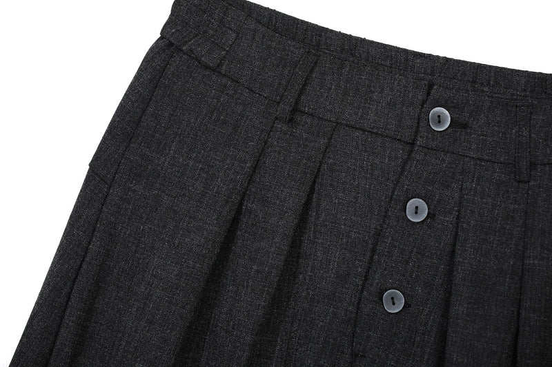Close-up of black pleated pants front waist with button placket