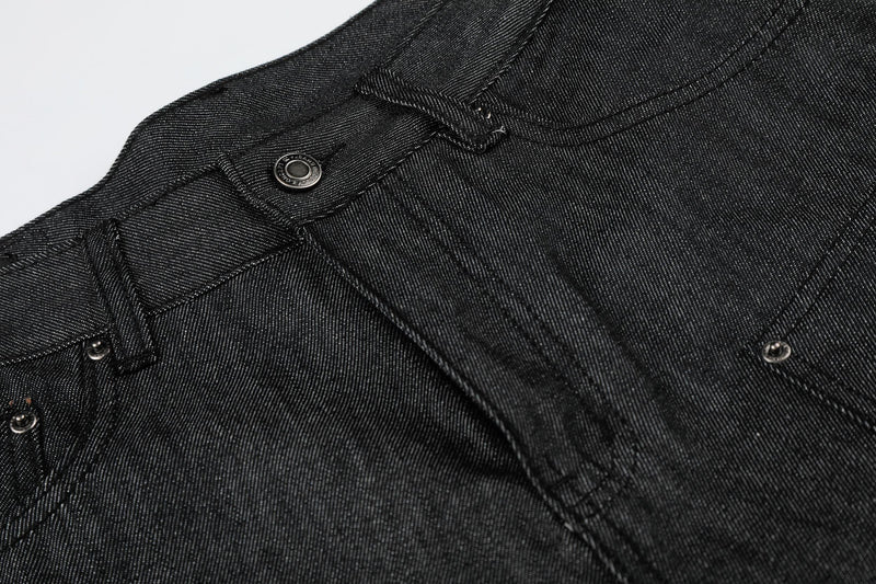 Close-up of black denim waistband with button closure, belt loop, and contrast stitching