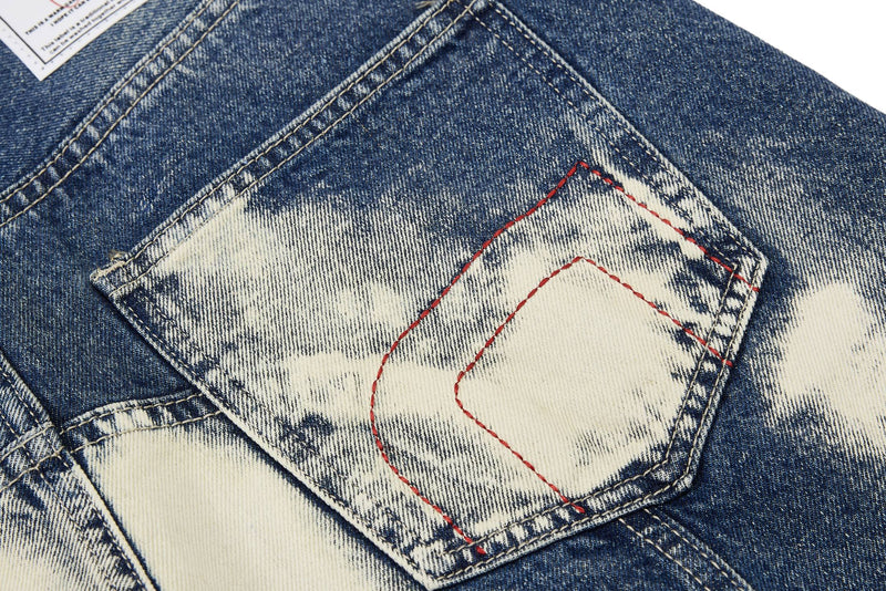 Close-up of back pocket with cream wash and red stitched outline on blue denim