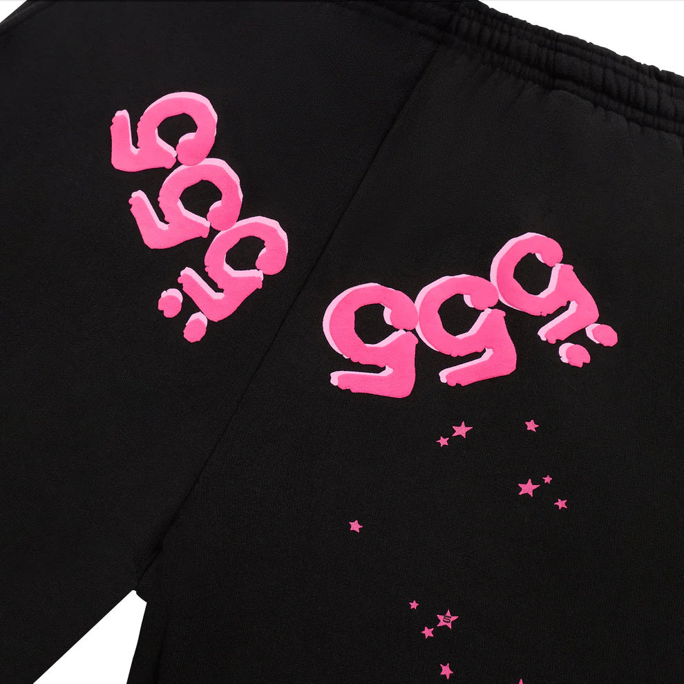 The 100% Cotton Sp5der Sweatpants are unisex black joggers featuring bold pink 999 logos and scattered stars on the upper back, giving these relaxed-fit streetwear pants a trendy, standout look.