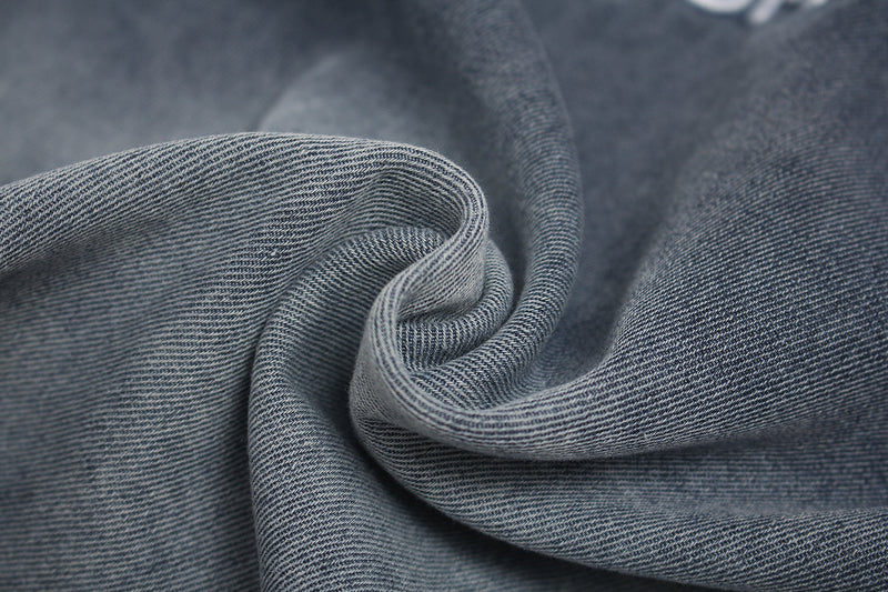 Close-up of vintage washed gray denim-like fabric with soft folded texture and distressed streetwear style