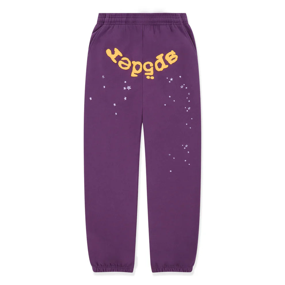The 100% Cotton Sp5der Sweatpants are unisex purple jogger pants with elastic cuffs and waistband, featuring a yellow upside-down "sp5der" logo near the top and small white star graphics on one leg for relaxed streetwear style.