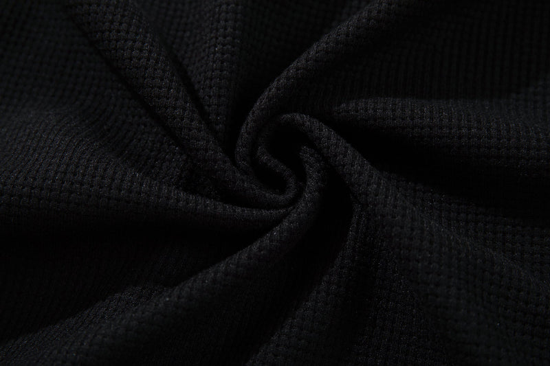 Close-up of black cotton tee fabric with a soft textured knit and subtle drape, styled for a punk graphic shirt