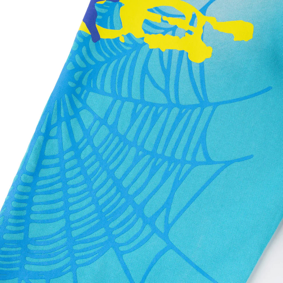 A close-up of 100% Cotton Sp5der Sweatpants shows blue jogger pants with a turquoise spider web graphic and yellow spider, plus star details—unisex, relaxed fit and perfect for streetwear styles.