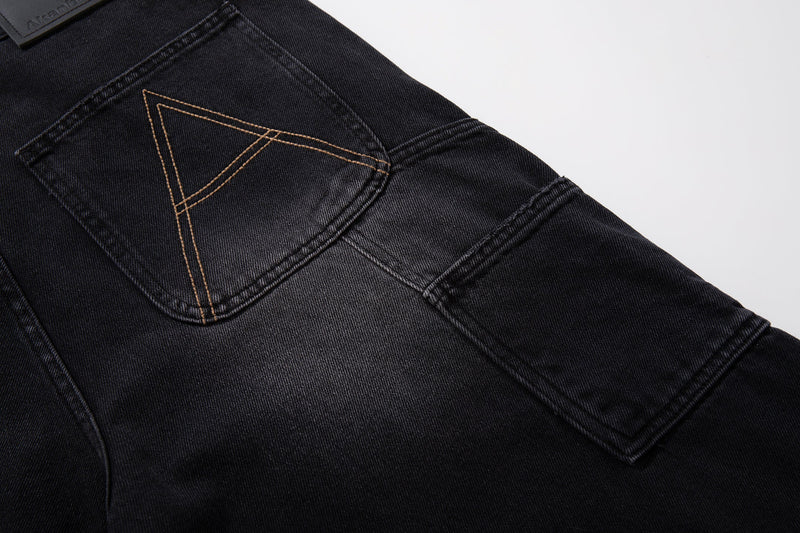 Close-up of back pocket and side seam on black carpenter jeans with tan stitched triangle detail