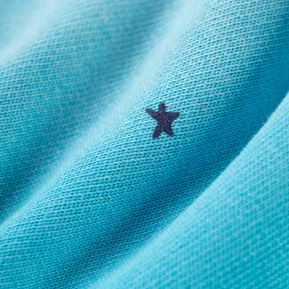 Close-up of 100% Cotton Sp5der Sweatpants—Unisex Blue Jogger Pants with a woven texture, relaxed fit, spider web graphic, and small star details. The fabric's gentle folds create soft shadows and highlights.