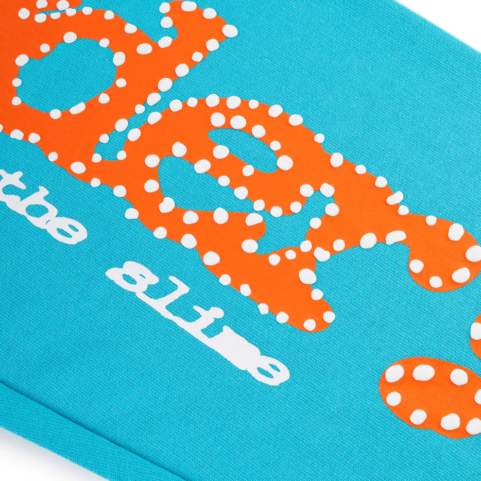 Close-up of orange logo print reading “be alive” on bright teal fabric, highlighting the bold style of 100% Cotton Sp5der Sweatpants—Unisex Jogger Pants with a relaxed fit, perfect for streetwear.