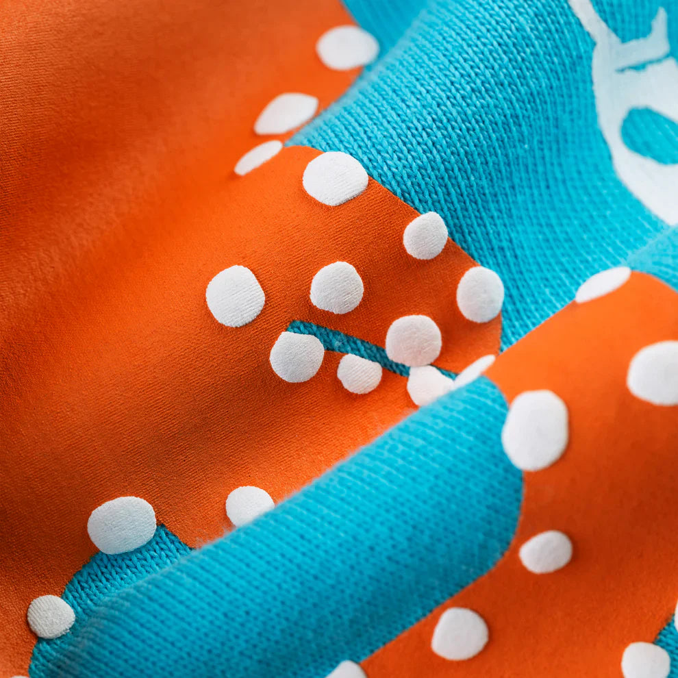 Close-up of 100% Cotton Sp5der Sweatpants—Unisex teal jogger pants with orange logo print and relaxed fit, showing their textured soft fabric. Ideal for streetwear fans who want unique and comfortable style.