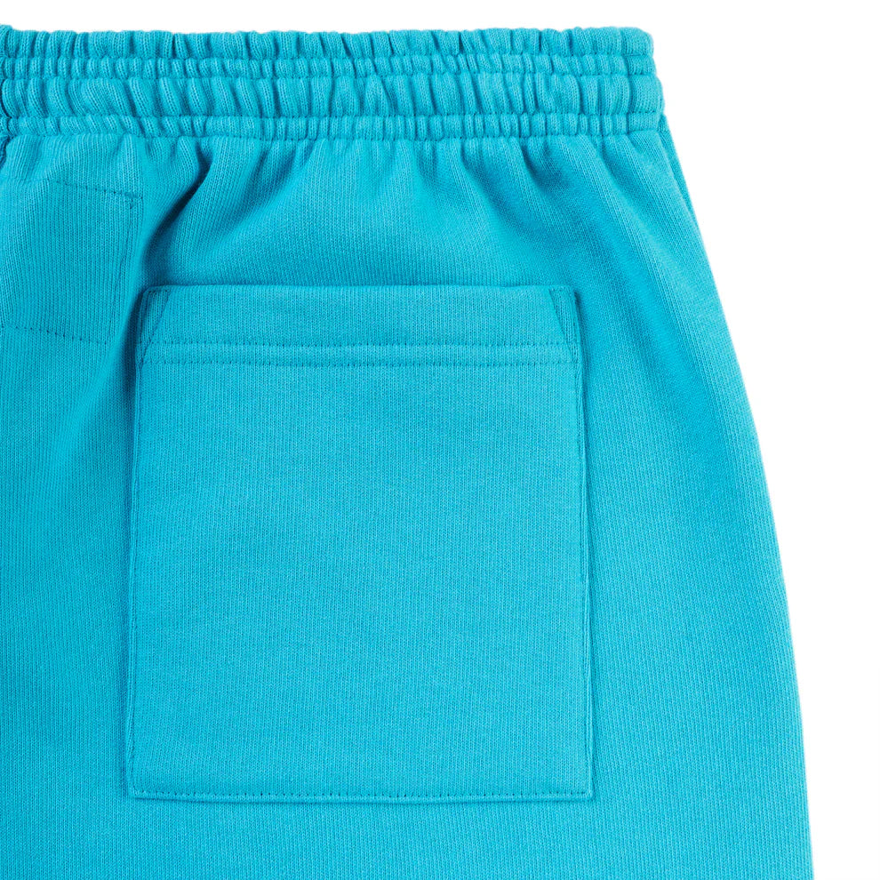 Close-up of 100% Cotton Sp5der Sweatpants—unisex teal jogger pants featuring an elastic waistband, large square patch pocket, orange logo print, and relaxed fit. Soft texture typical of streetwear.