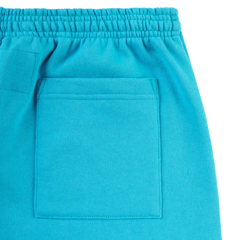 Close-up of 100% Cotton Sp5der Sweatpants—unisex teal jogger pants featuring an elastic waistband, large square patch pocket, orange logo print, and relaxed fit. Soft texture typical of streetwear.