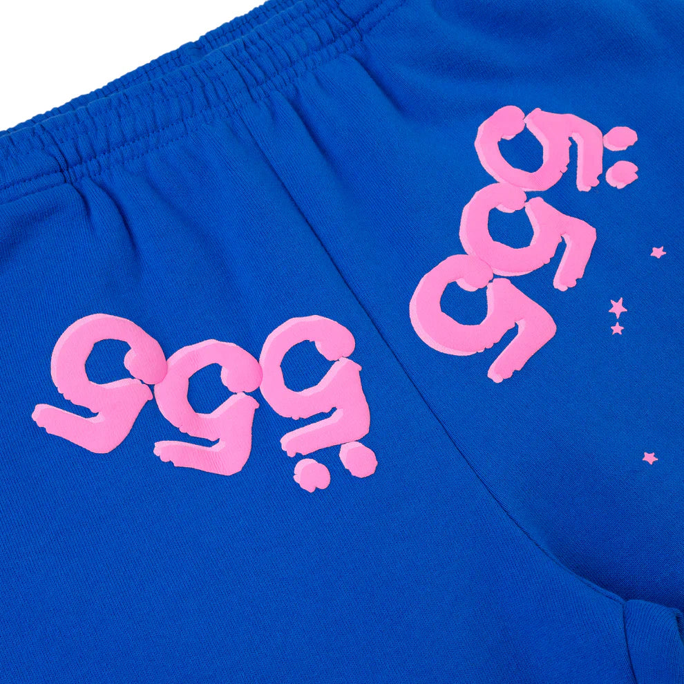 Close-up of 100% Cotton Sp5der Sweatpants—unisex blue jogger pants with pink logo graphics and star accents, in a relaxed fit.