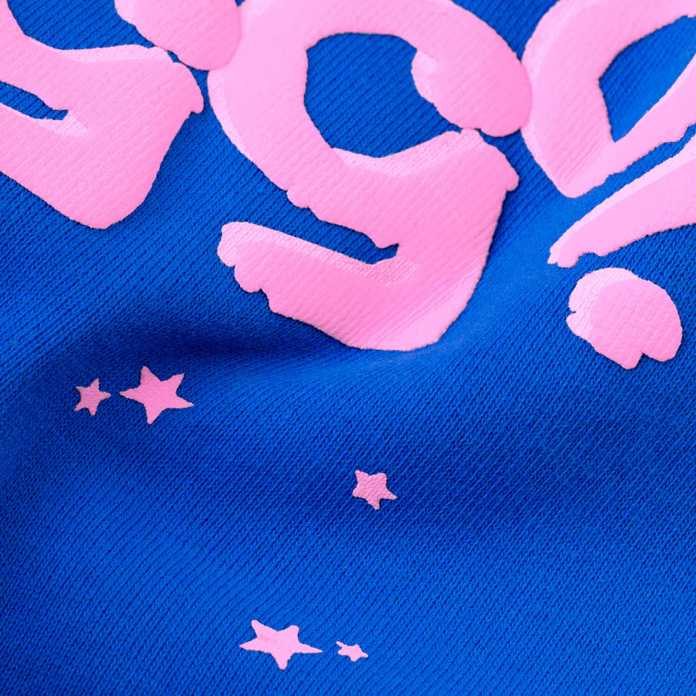 Close-up of the 100% Cotton Sp5der Sweatpants—Unisex Blue Jogger Pants with pink logo and star accents—showing visible cotton texture, playful raised pink lettering, stylish folds, and a relaxed fit.
