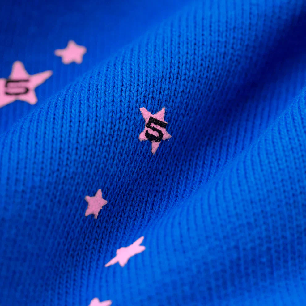 Close-up of the 100% Cotton Sp5der Sweatpants—unisex blue jogger pants with a soft, knitted texture and pink logo star accents, including some stars featuring the number 5. Relaxed fit for streetwear comfort.