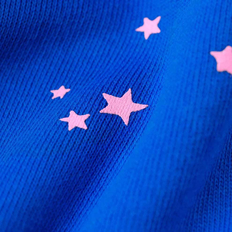 Close-up of 100% Cotton Sp5der Sweatpants – Unisex Blue Jogger Pants with Pink Logo and star accents in a relaxed fit, highlighting the bold royal blue ribbed fabric and distinctive light pink printed stars.