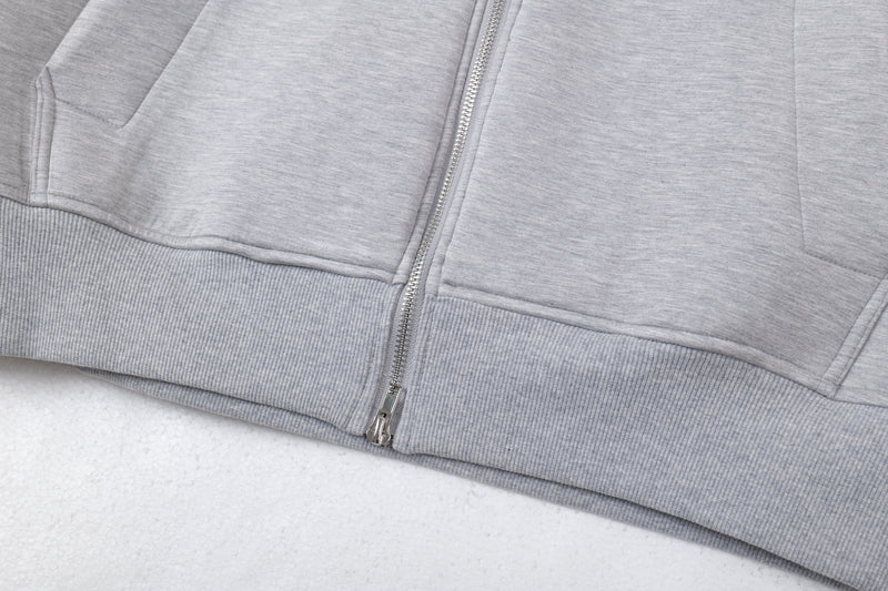 Close-up of lower front zipper and ribbed hem on light gray hoodie