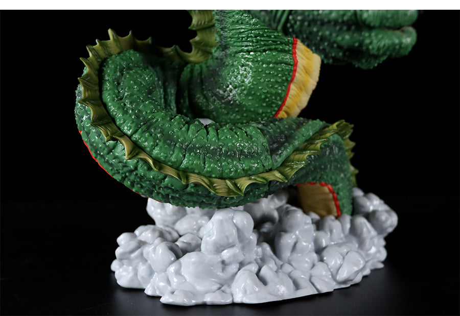 A close-up of the Seakoff Shenron Broly Collectible Figure from Dragon Ball Z shows a detailed green tail with textured scales and yellow undersides. The tail curves upward on a base resembling white, jagged rocks against a black background. This premium figure stands 37cm tall.