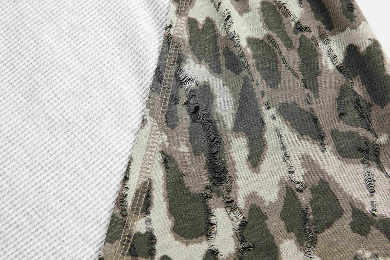 Close-up of camouflage sleeve seam beside white waffle-knit body panel