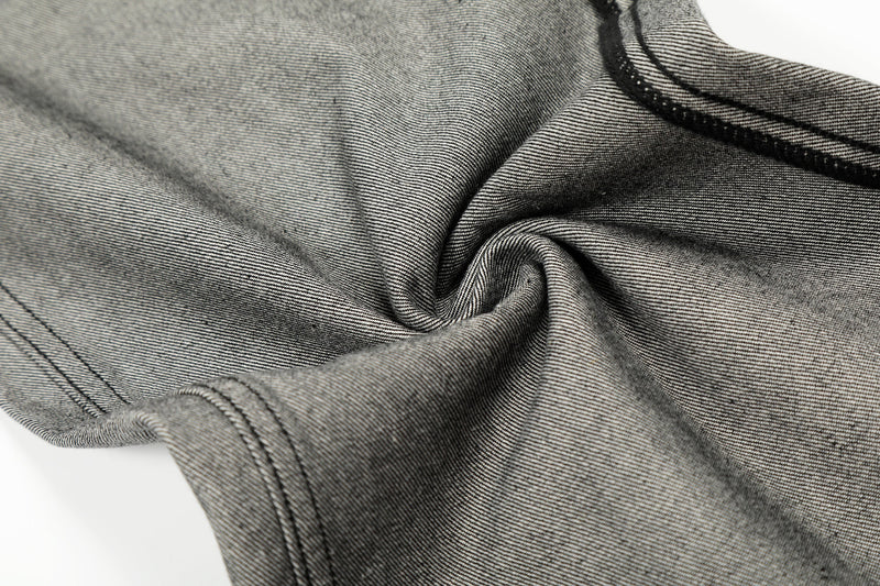 Close-up of gray denim fabric texture and seam stitching near the leg opening