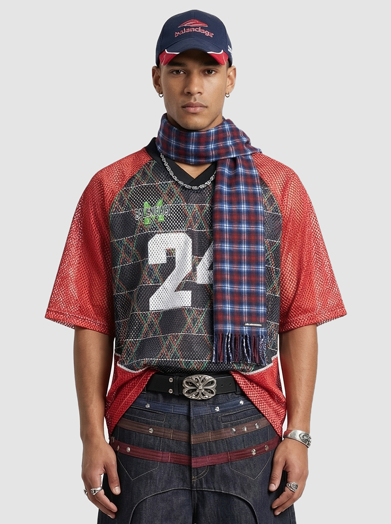Model wearing a red mesh varsity jersey T-shirt with black number 24, paired with a plaid scarf and cap, streetwear styling