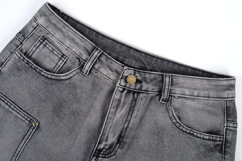 Close-up of grey denim waistband with button closure, belt loops, and front pocket edge