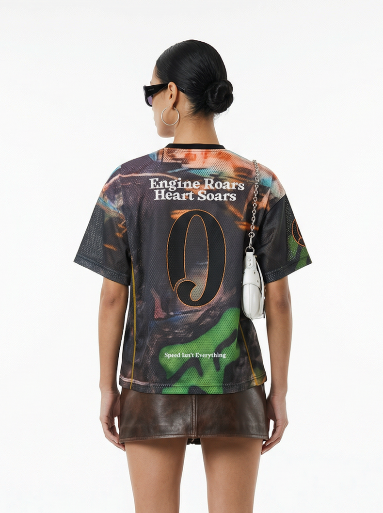 Back view of model wearing a racing mesh jersey with bold graphic print, leather mini skirt, and white shoulder bag