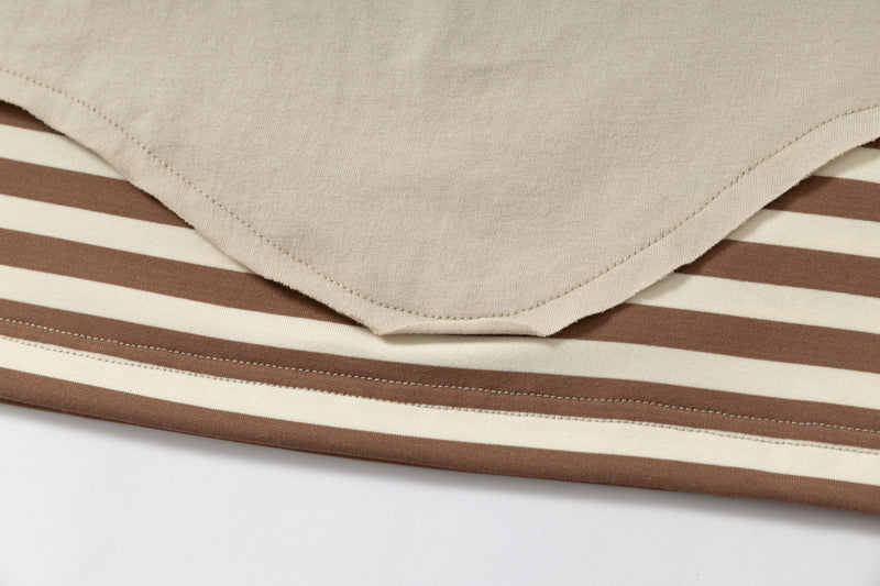 Close-up of a beige layered graphic tee with brown and cream striped hem detailing