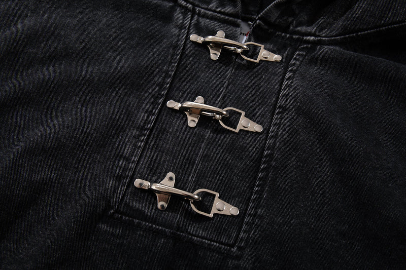 Close-up of three silver metal toggle closures on black denim hoodie