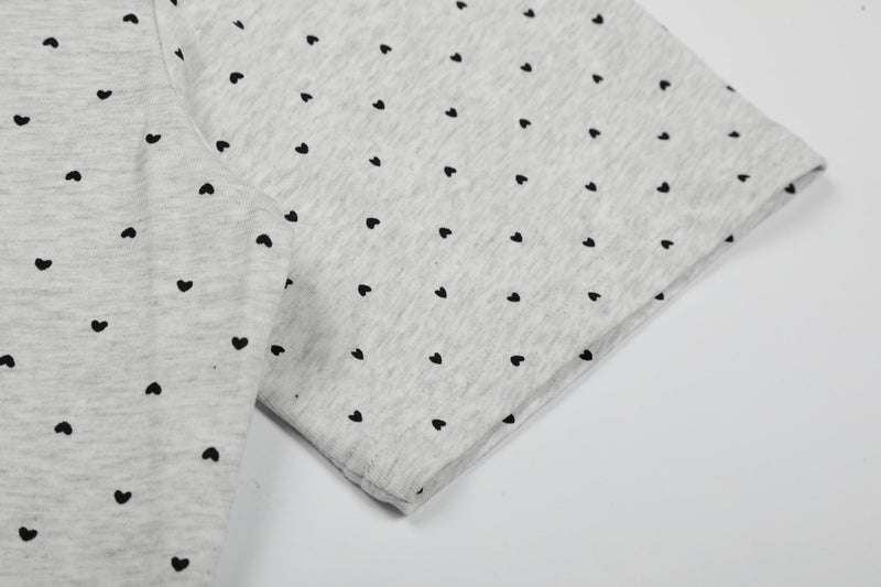 Light gray relaxed tee with allover black micro heart print and folded short sleeves on a clean white background