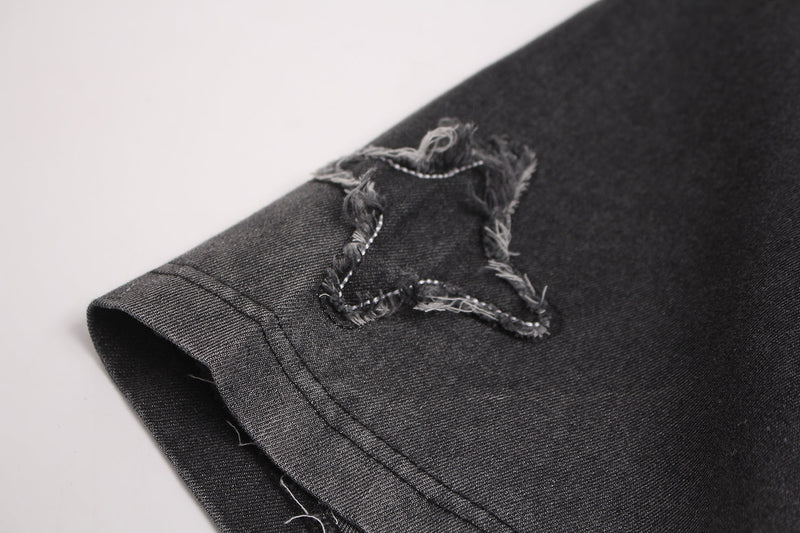 Black vintage-washed T-shirt sleeve with distressed frayed star patch detail and raw streetwear styling