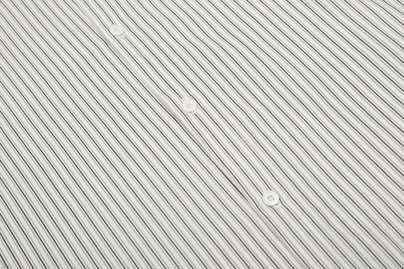 Close-up of an off-white pinstripe button-up shirt with subtle patch details and white buttons
