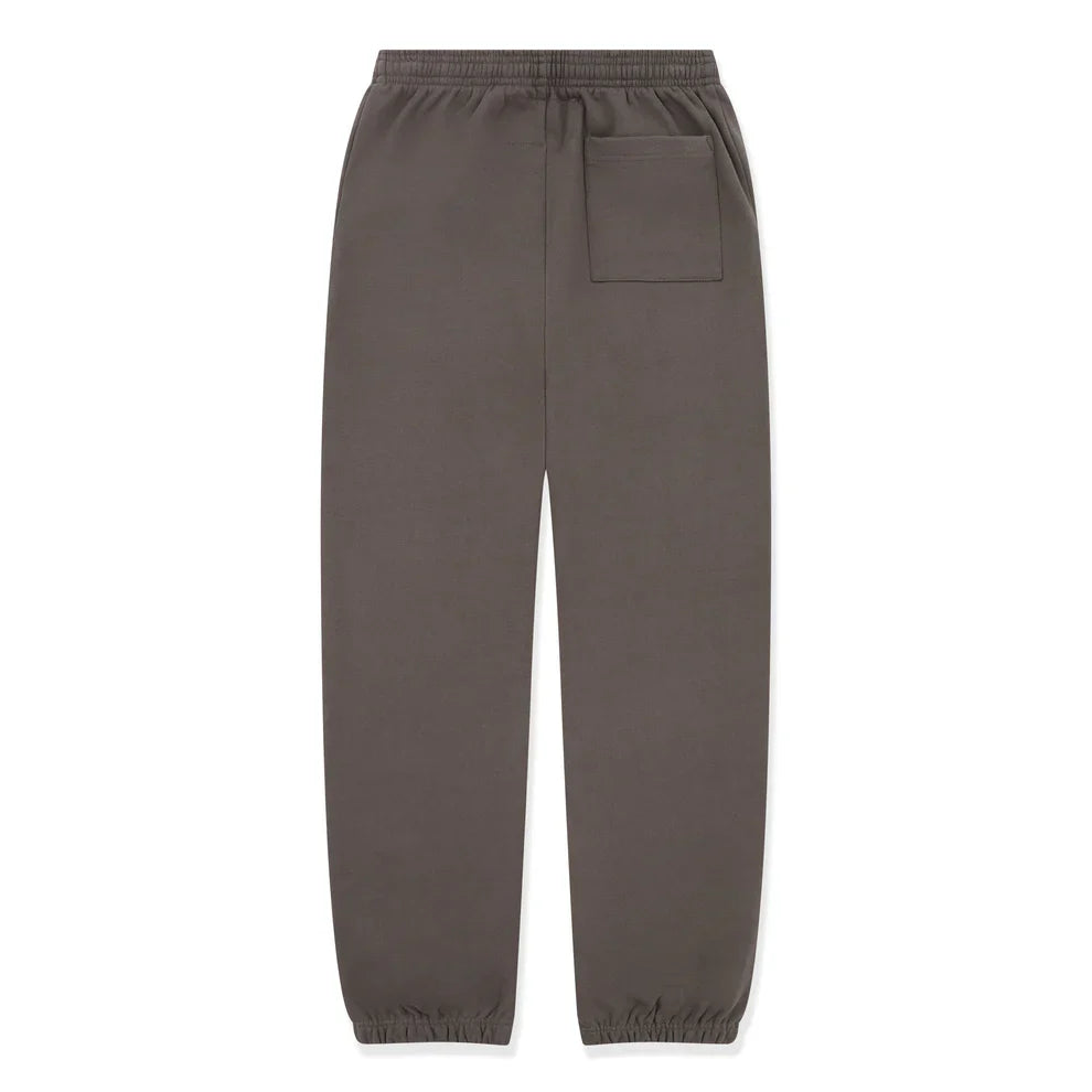 A pair of Sp5der Sweatpants – unisex dark grey cotton joggers with a green side logo, star print, elastic waistband and cuffs, plus a back right patch pocket – are laid flat on a white background.
